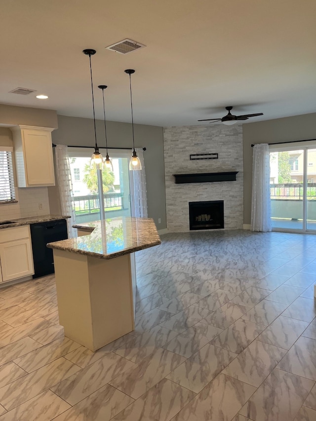 kitchen with light stone counters, plenty of natural light, white cabinets, and black dishwasher