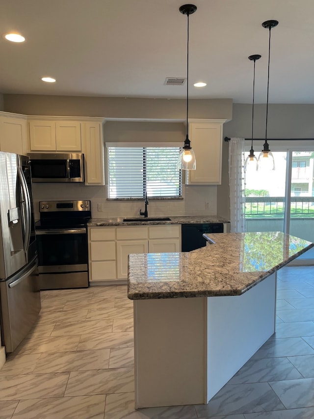 kitchen with appliances with stainless steel finishes, white cabinetry, a wealth of natural light, and sink