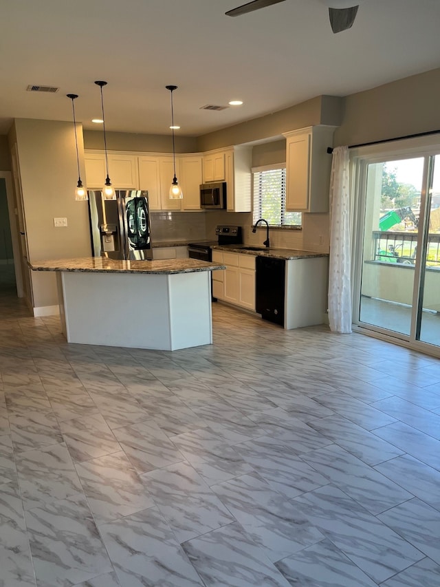 kitchen featuring decorative light fixtures, a kitchen island, white cabinetry, and black appliances