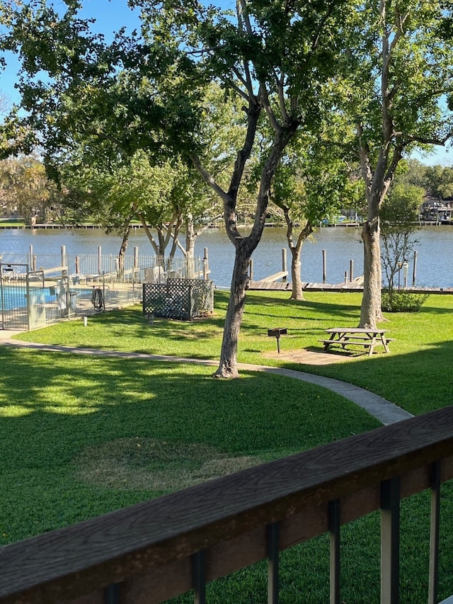 surrounding community with a water view and a lawn