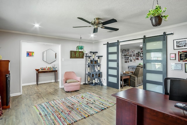 home office featuring a barn door, light hardwood / wood-style flooring, and crown molding