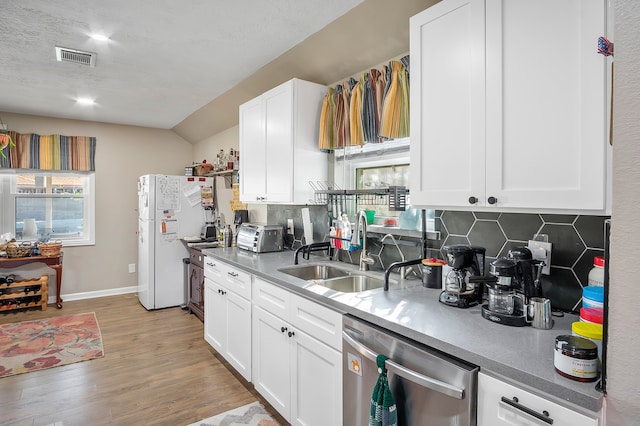 4515 Ponca St, Pasadena, TX 77504 - kitchen with dishwasher, freestanding refrigerator, a sink, light wood finished floors, and decorative backsplash