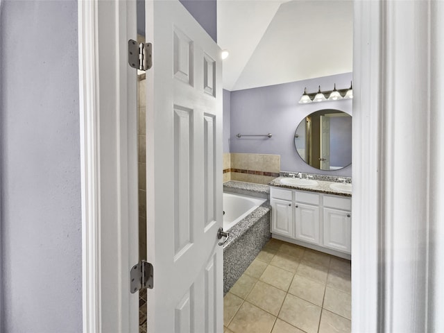 bathroom featuring a tub to relax in, tile patterned flooring, vanity, and vaulted ceiling