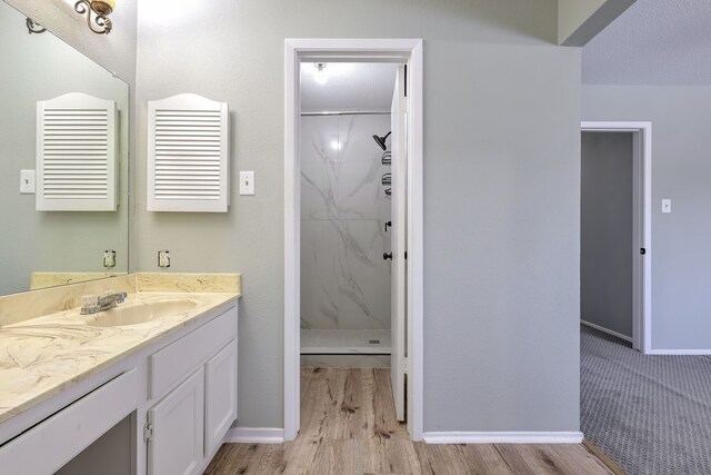 bathroom with a shower, a textured ceiling, vanity, and hardwood / wood-style flooring