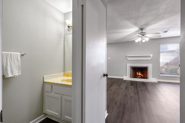 bathroom with a textured ceiling, vanity, hardwood / wood-style flooring, and ceiling fan