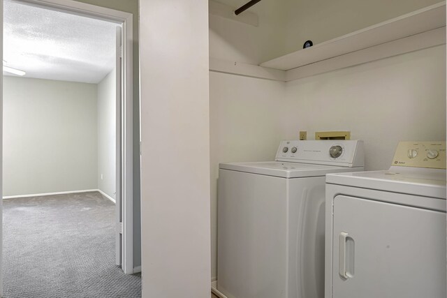 clothes washing area featuring a textured ceiling, carpet floors, and washing machine and clothes dryer