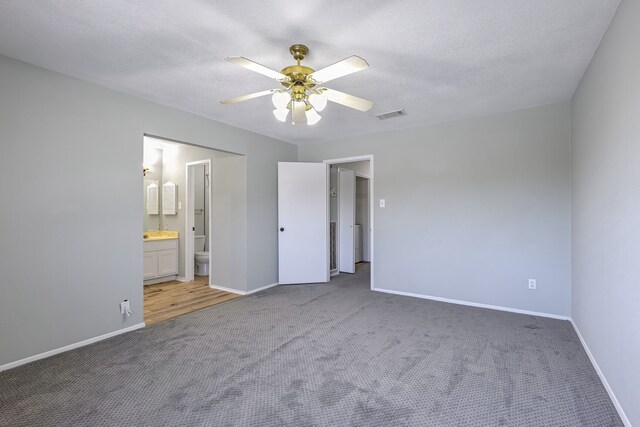 unfurnished bedroom with ensuite bath, ceiling fan, carpet, and a textured ceiling