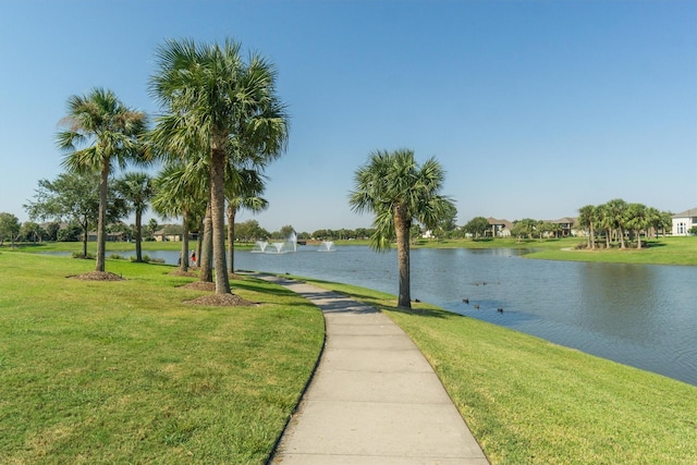 view of property's community with a lawn and a water view