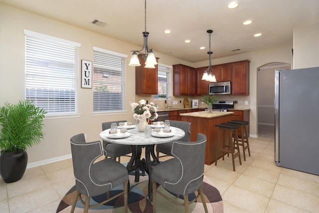 kitchen featuring a wealth of natural light, stainless steel appliances, a kitchen island, and hanging light fixtures