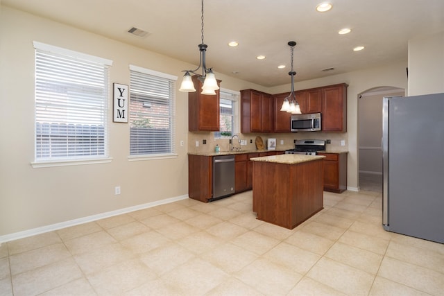 kitchen with pendant lighting, a center island, stainless steel appliances, and plenty of natural light