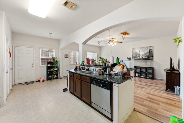 kitchen with dark stone counters, light hardwood / wood-style flooring, stainless steel dishwasher, decorative light fixtures, and dark brown cabinetry