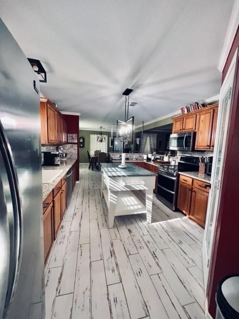 kitchen with light wood-type flooring, backsplash, stainless steel appliances, pendant lighting, and a notable chandelier