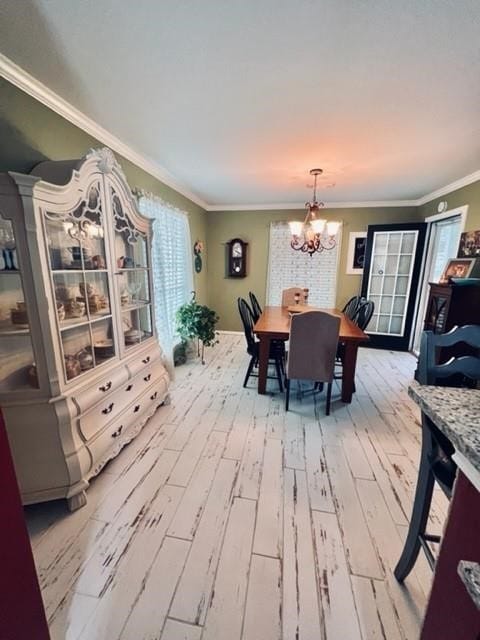 dining area featuring a notable chandelier, ornamental molding, a wealth of natural light, and light hardwood / wood-style flooring