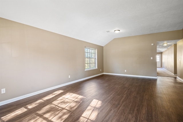 spare room featuring dark hardwood / wood-style flooring and vaulted ceiling