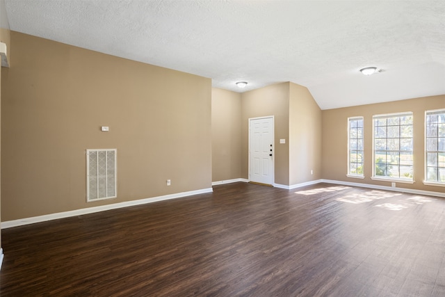 unfurnished room with dark hardwood / wood-style floors, a textured ceiling, and vaulted ceiling