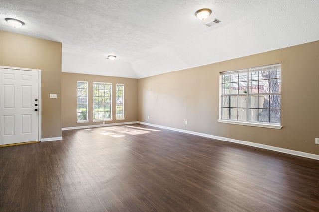 unfurnished living room with dark hardwood / wood-style floors, a healthy amount of sunlight, lofted ceiling, and a textured ceiling