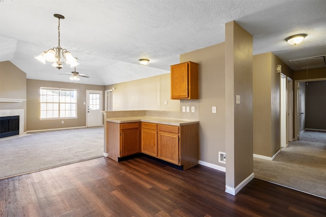 kitchen featuring kitchen peninsula, ceiling fan with notable chandelier, dark wood-type flooring, and vaulted ceiling