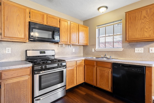 kitchen with black appliances, dark hardwood / wood-style floors, sink, and a textured ceiling