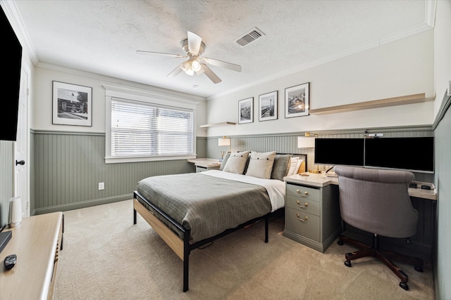 bedroom with wood walls, crown molding, ceiling fan, a textured ceiling, and light colored carpet