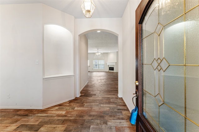 hallway with a chandelier and dark hardwood / wood-style floors