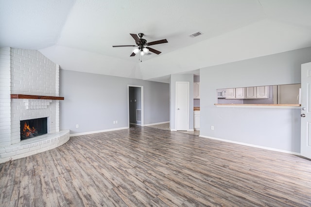 unfurnished living room with a fireplace, hardwood / wood-style flooring, ceiling fan, and lofted ceiling