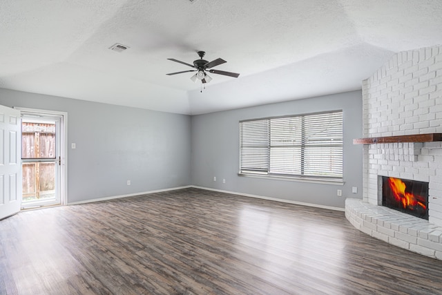 unfurnished living room featuring lofted ceiling, dark wood-type flooring, ceiling fan, a textured ceiling, and a fireplace