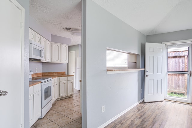 kitchen with white cabinets, white appliances, light hardwood / wood-style flooring, and a healthy amount of sunlight