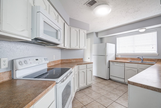 kitchen with a textured ceiling, white appliances, sink, light tile patterned floors, and white cabinetry