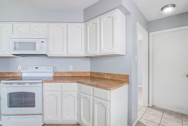 kitchen with a textured ceiling, light tile patterned floors, white cabinets, and white appliances