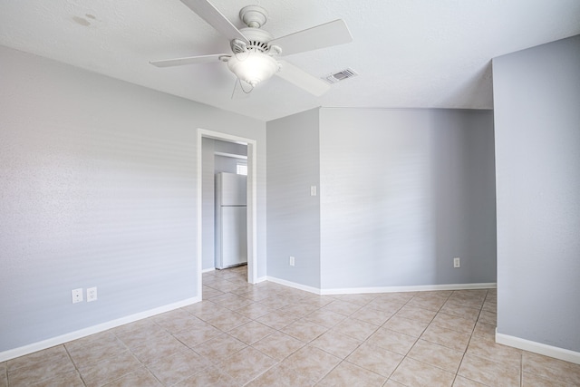 empty room with a textured ceiling, ceiling fan, and light tile patterned flooring