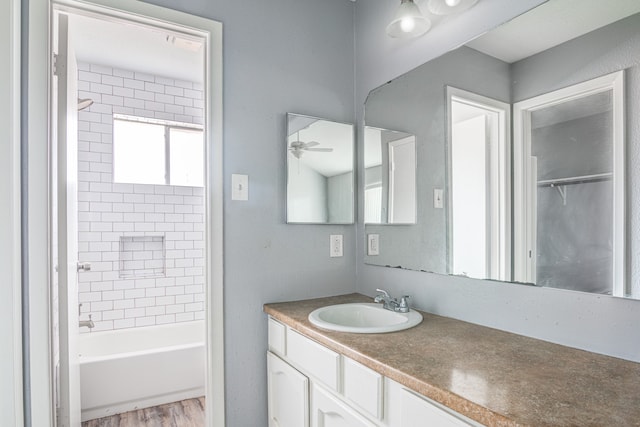 bathroom featuring wood-type flooring, vanity, tiled shower / bath combo, and ceiling fan