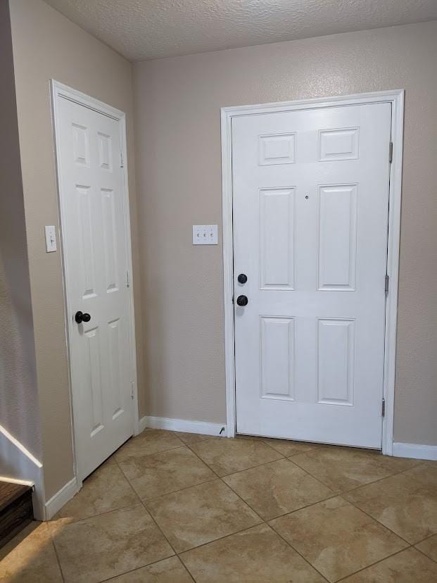 entryway featuring light tile patterned floors and a textured ceiling