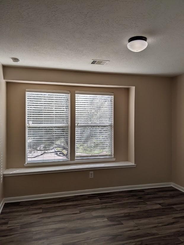 unfurnished room featuring a textured ceiling and dark hardwood / wood-style floors