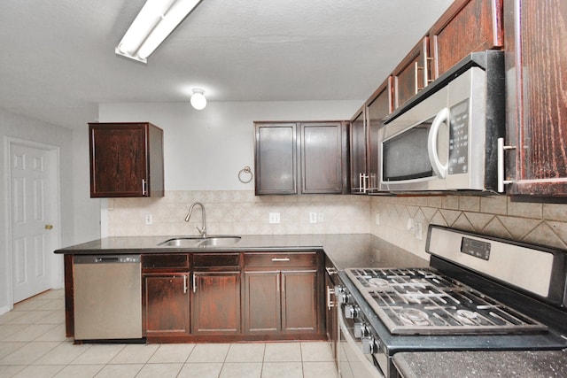 kitchen featuring backsplash, sink, light tile patterned floors, and stainless steel appliances