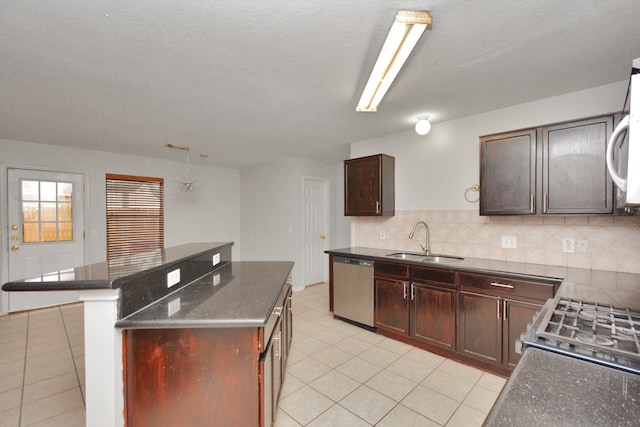 kitchen featuring decorative backsplash, a textured ceiling, stainless steel appliances, sink, and a kitchen island