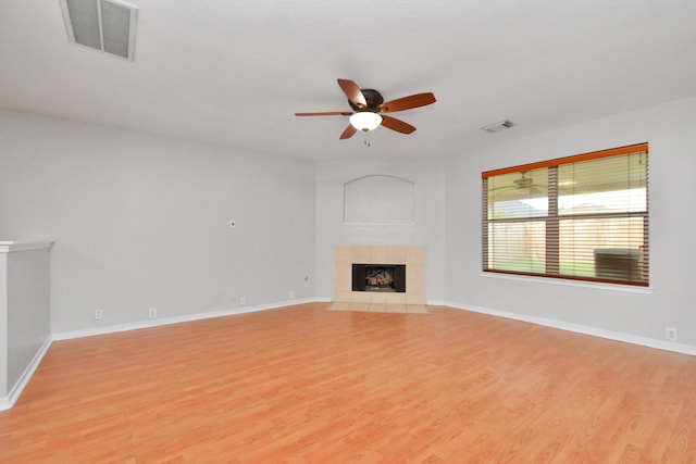 unfurnished living room with a tile fireplace, ceiling fan, and light hardwood / wood-style floors