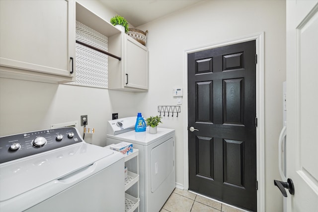 clothes washing area featuring washer and dryer, cabinet space, and light tile patterned flooring