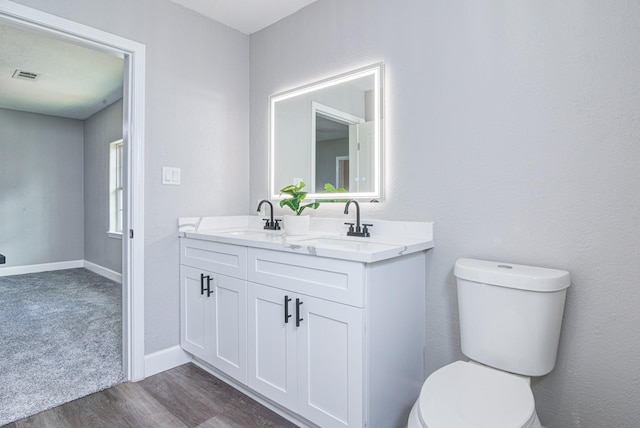 bathroom with toilet, vanity, and hardwood / wood-style flooring