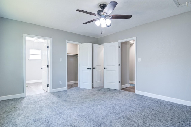 unfurnished bedroom with carpet, a walk in closet, a closet, ceiling fan, and ensuite bathroom