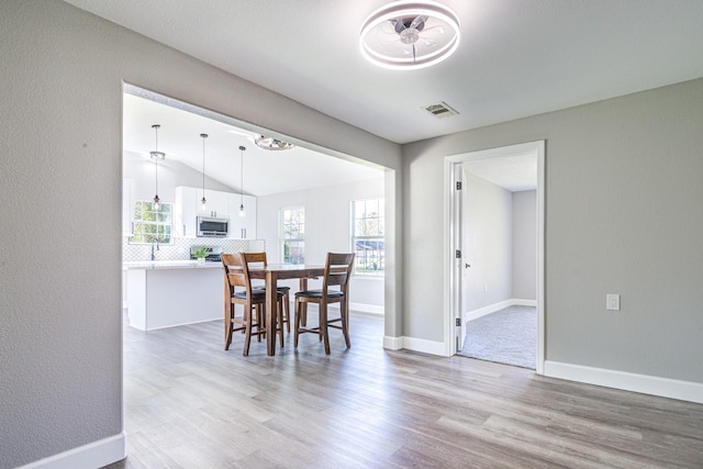 dining room featuring light wood-type flooring and vaulted ceiling