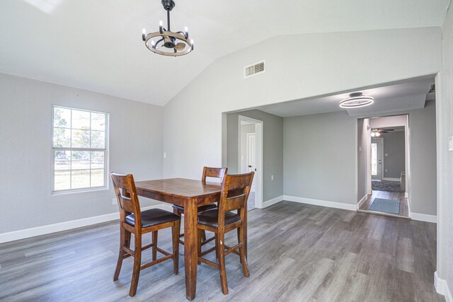 dining area featuring vaulted ceiling, dark hardwood / wood-style flooring, and ceiling fan with notable chandelier