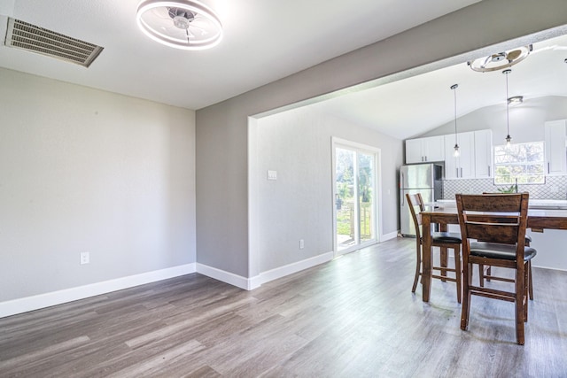 dining area featuring vaulted ceiling and light wood-type flooring