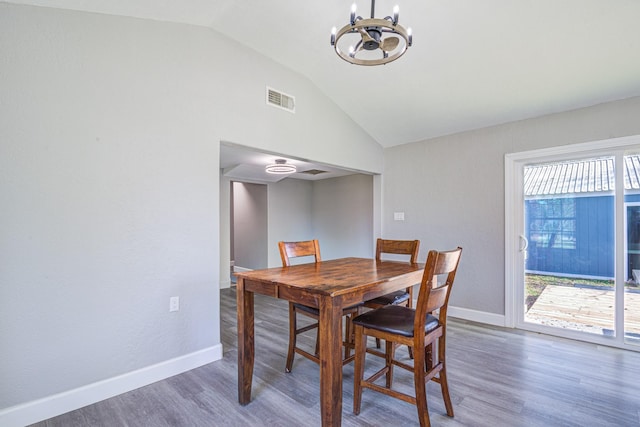 dining space with dark hardwood / wood-style flooring, a notable chandelier, and vaulted ceiling