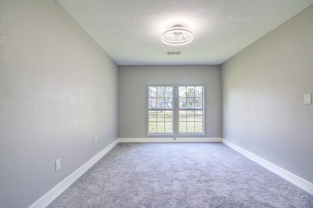 carpeted empty room featuring a textured ceiling