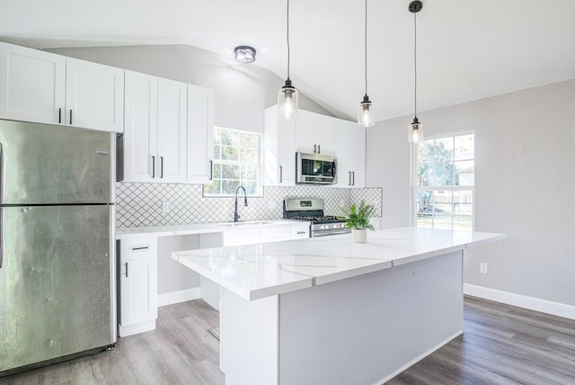 kitchen featuring vaulted ceiling, stainless steel appliances, and white cabinetry