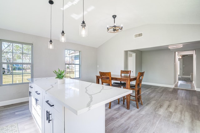 kitchen featuring white cabinetry, pendant lighting, plenty of natural light, and light stone countertops