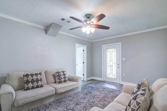 living room featuring ceiling fan, hardwood / wood-style flooring, ornamental molding, and a textured ceiling