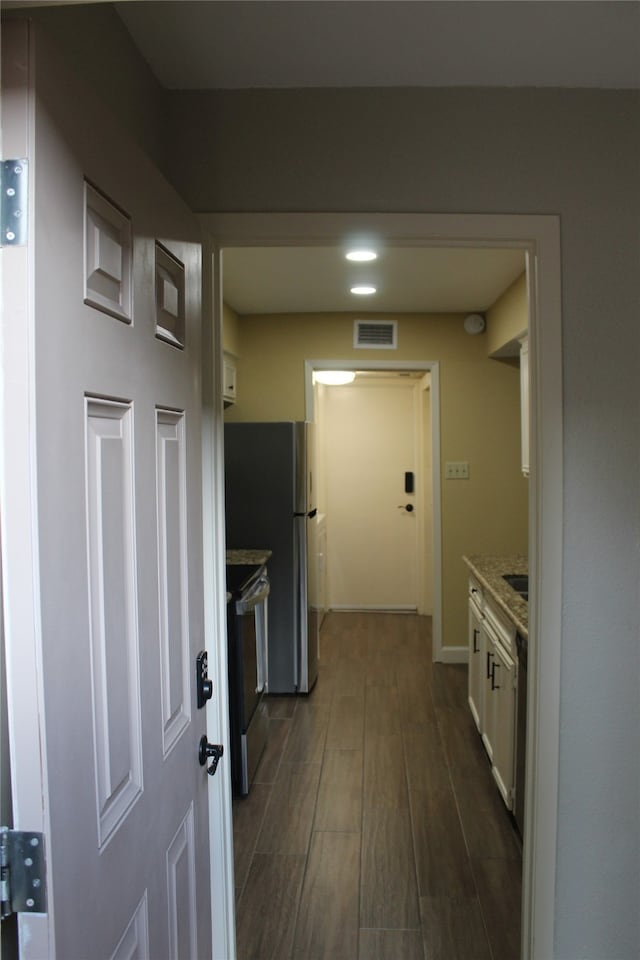 kitchen with electric range, light stone counters, and white cabinetry