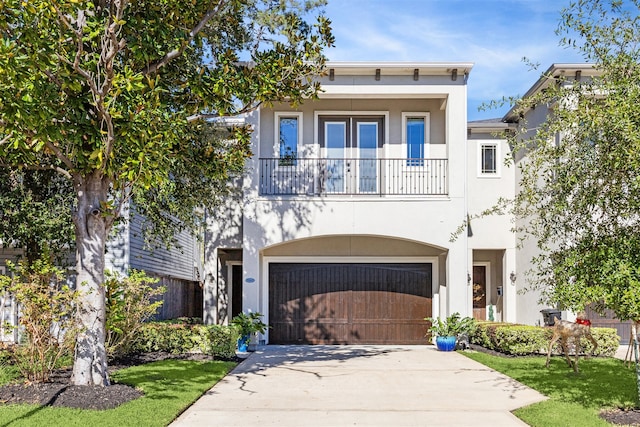 view of front of property featuring a balcony, a front lawn, and a garage