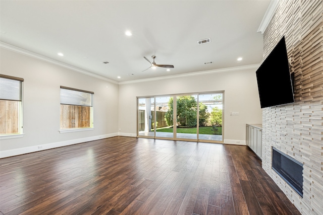 unfurnished living room with a stone fireplace, crown molding, dark hardwood / wood-style flooring, and ceiling fan